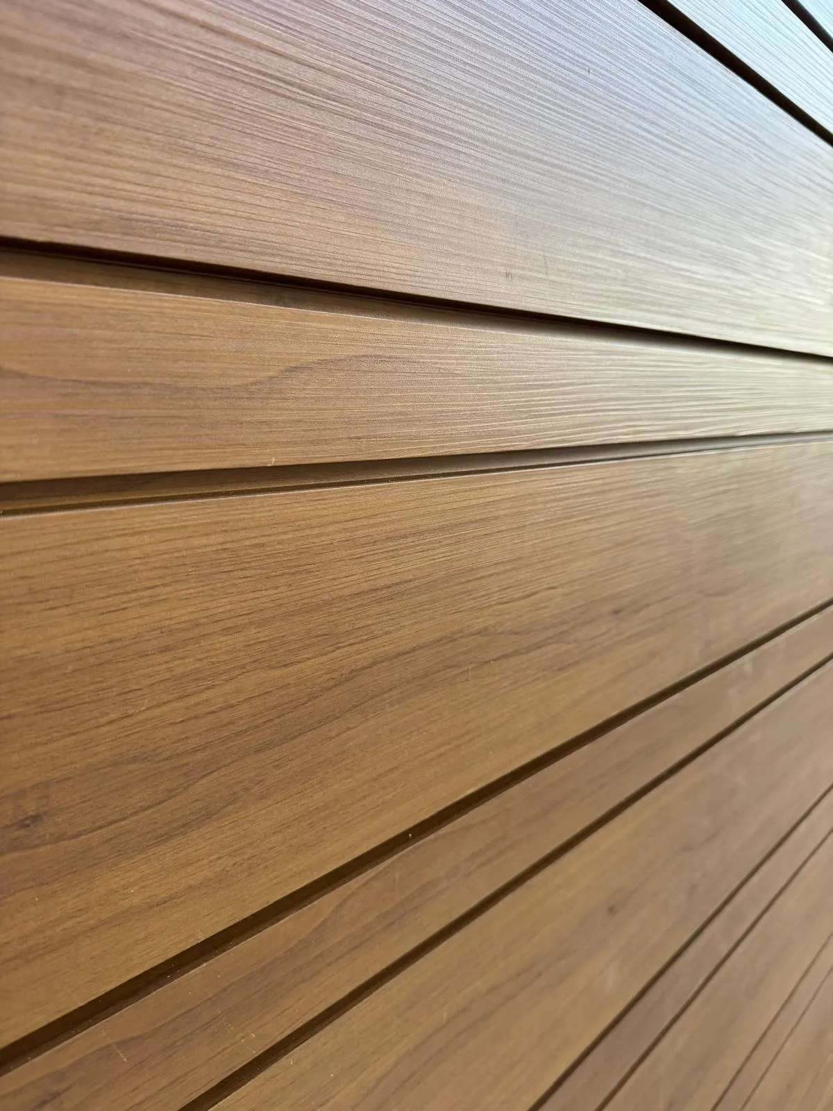 Installed wood-grain aluminum siding panels showing realistic teak-tone grain and color depth after the sublimation finishing process