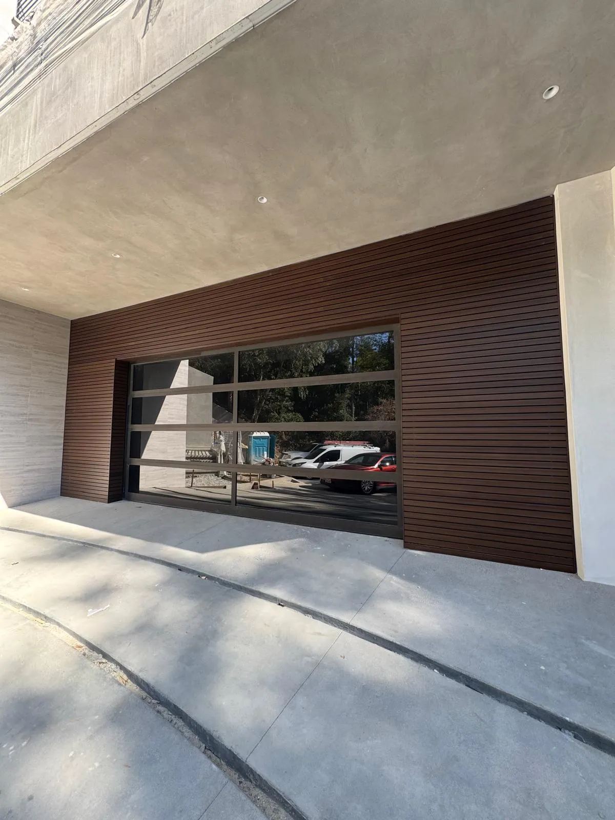 Wenge wood-grain aluminum cladding installed on a Hollywood Hills residence with horizontal slat coursing around a glass garage door