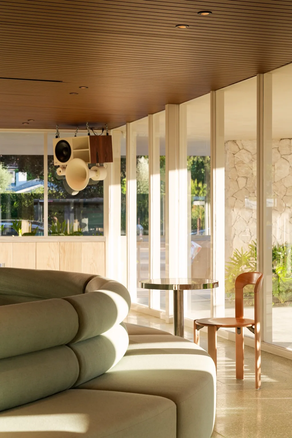 Wood-look aluminum ceiling extending toward the glazed storefront edge