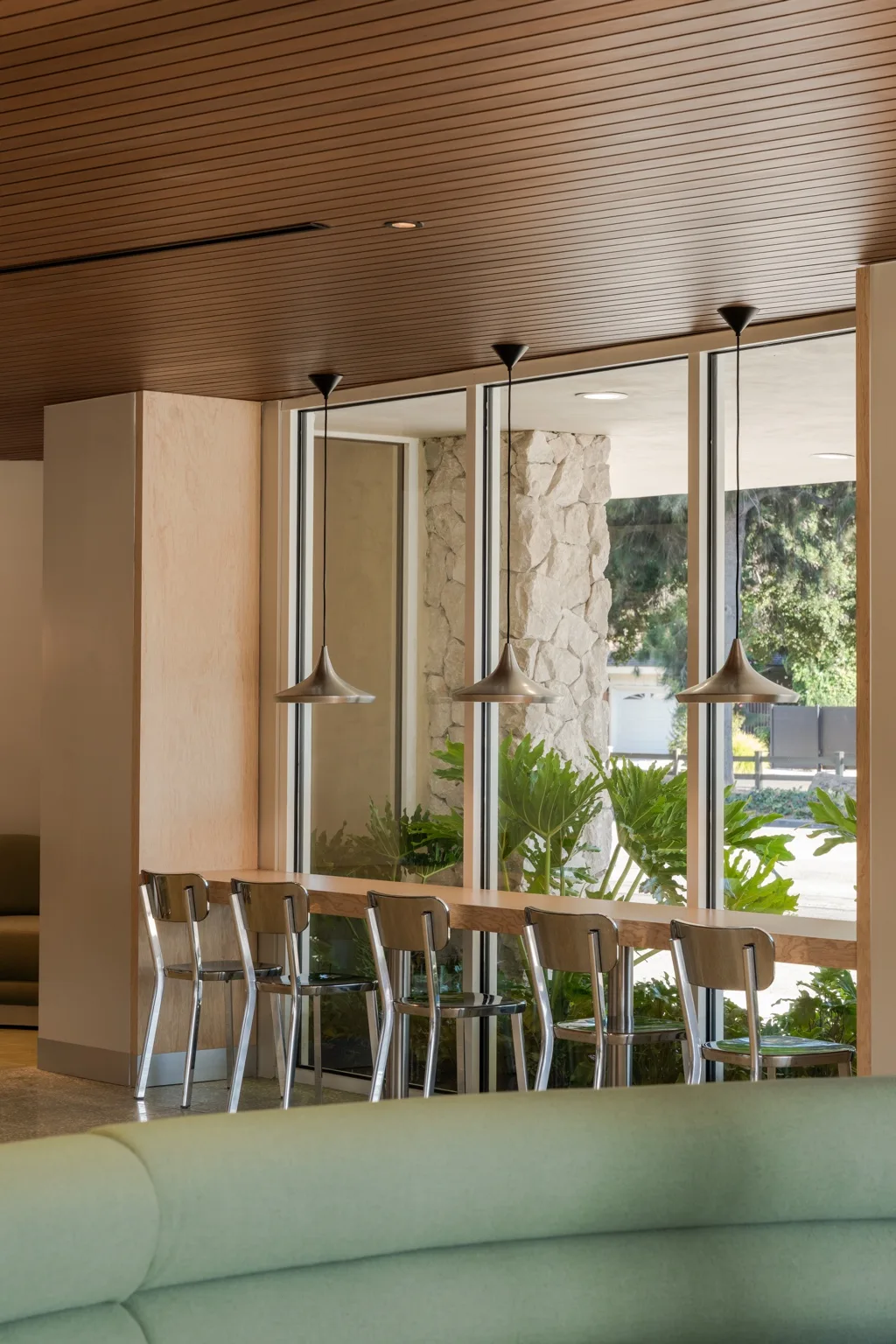 Warm wood-look aluminum ceiling lines framing window seating and pendant lights