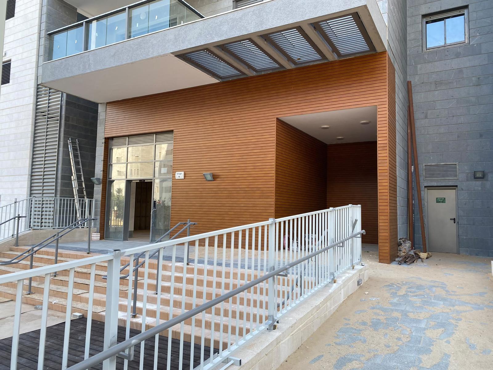 Warm wood-grain aluminum cladding on a building entrance, a low-maintenance exterior cladding material