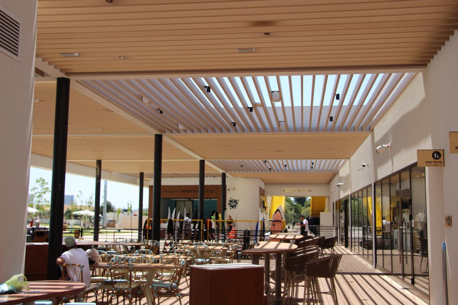 Wood-look aluminum ceiling and slatted pergola over an outdoor commercial dining area