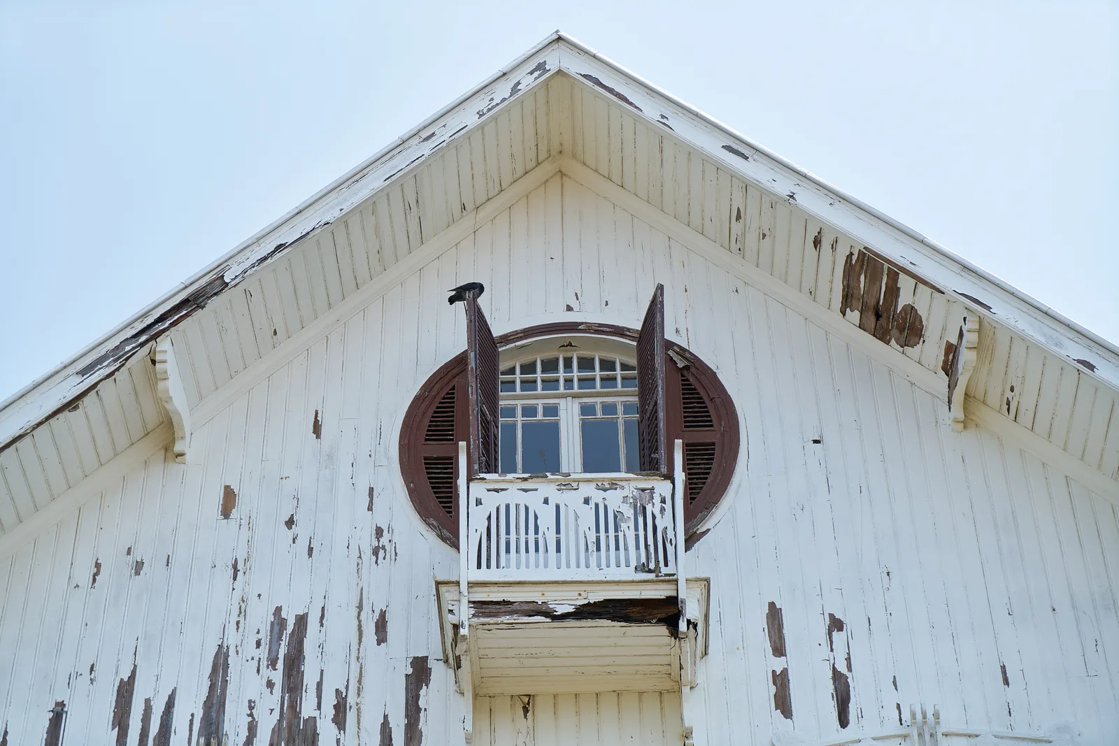 Weathered wood siding with peeling paint and rot, the decay and maintenance problem aluminum cladding avoids